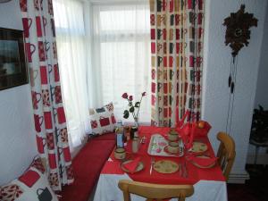 mesa de comedor con mantel rojo y blanco en El Tabora Guest House en St. Peter Port