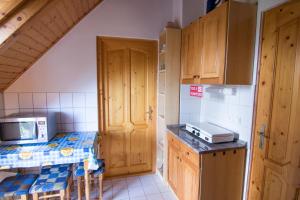 a small kitchen with wooden cabinets and a microwave at Vulcano Vendégház in Kisapáti