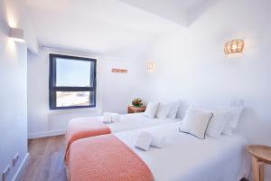 two beds in a white room with a window at The Salty Lodge in Lagos