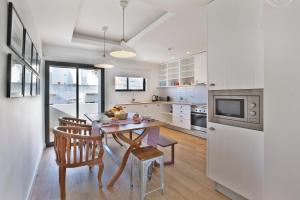 a white kitchen with a wooden table and chairs at The Salty Lodge in Lagos