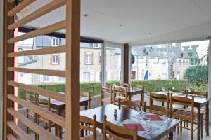 un restaurante con mesas, sillas y ventanas grandes en Hotel du 6 juin, en Sainte-Mère-Église