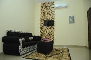a living room with a black couch and a tv at Leading Wings Beach Apartments in Sur