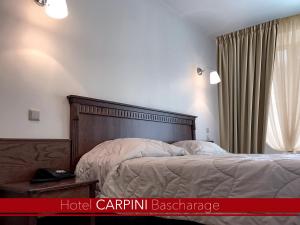 łóżko z drewnianym zagłówkiem w sypialni w obiekcie Hotel Carpini w mieście Bascharage