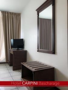 a hotel room with a mirror and a tv at Hotel Carpini in Bascharage