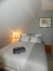 uma grande cama branca com um saco preto em L'Eugenie em Pierrefonds