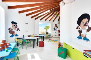 uma sala de aula com mesas e cadeiras com personagens de desenhos animados nas paredes em Alcudia Garden Aparthotel em Port d'Alcudia