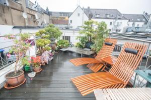 Apartement mit Dachterrasse - bei Curth klingen - Teilen Sie uns Ihre Ankunfszeit mit في دوسلدورف: شرفة مع كراسي ونباتات الفخار على مبنى