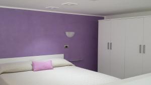 purpurowa sypialnia z białym łóżkiem i fioletową ścianą w obiekcie Taormina Rainbow House w Taominie +37 zdjęć