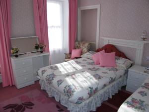 a bedroom with a bed with pink pillows at El Tabora Guest House in St Peter Port