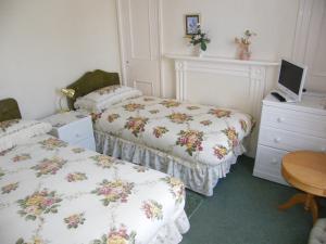 a bedroom with two beds and a desk with a computer at El Tabora Guest House in St Peter Port