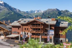 a large wooden building with mountains in the background at CGH Résidences & Spas Le Lodge Hemera in La Rosière