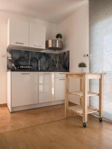 a kitchen with white cabinets and a wooden table at Apartments Nino 1 in Zadar