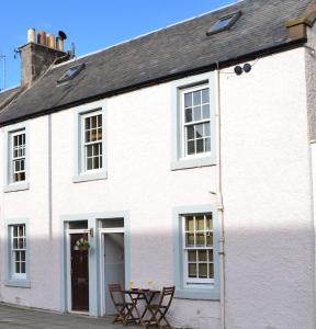 a white house with a table and chairs in front of it at Fishermans flat - River view holiday home in Dundee