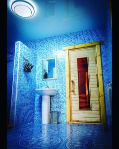 a blue tiled bathroom with a sink and a door at Hotel Bannyi Dvor in Uzyn