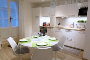 a kitchen with a table and chairs and a kitchen with white cabinets at Arles Getaway - La Suite Arlésienne in Arles +9 photos