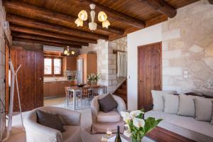 a living room with a couch and chairs and a kitchen at Spilia Village Hotel & Villas in Spiliá