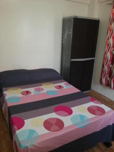 a bedroom with a bed with a colorful blanket on it at Budget Studio Unit in Makati in Manila