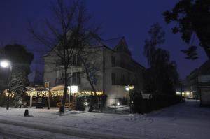 a building with christmas lights in the snow at night at Pensjonat Lazur in Mielno
