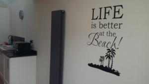 a wall with a sign that reads life is better at the beach at Chloe Cottage in Whitstable