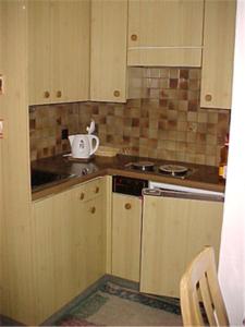 cocina con armarios de madera y horno con fogones en Haus Brüggli B24, en Arosa