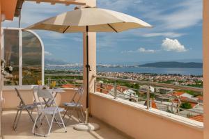 a balcony with an umbrella and a table and chairs at Panorama Holidays in Kaštela