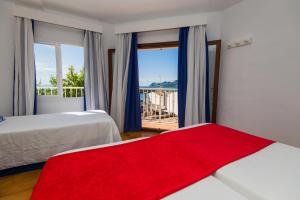 sypialnia z 2 łóżkami i oknem z czerwonym kocem w obiekcie Hostal Cala Ratjada w Cala Ratjada