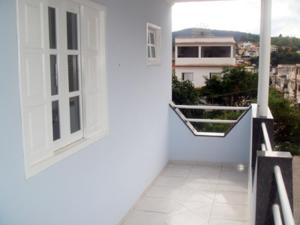 einen Balkon in einem weißen Gebäude mit Fenster in der Unterkunft Pousada Afonso Cláudio in Afonso Cláudio