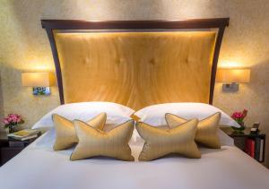 a bed with a large wooden headboard and four pillows at Ten Manchester Street Hotel in London