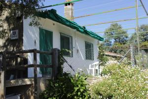 a white house with a green door and a fence at Casa Rural El Tejar in Higuera de la Sierra