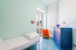 um quarto com uma cómoda azul e uma cadeira laranja em La Luella em Sorrento