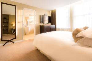 1 dormitorio con 1 cama blanca grande y espejo en Ten Manchester Street Hotel en Londres
