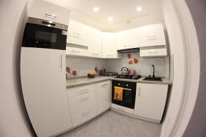 una cocina con armarios blancos y un aparato negro en Family Apartments, en Racibórz