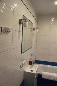 a bathroom with a sink and a mirror and a tub at Family Apartments in Racibórz