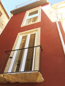 ein rotes Gebäude mit einem Fenster und einem Balkon in der Unterkunft Casa Amarela in Aveiro