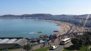 a crowd of people on a beach near a body of water at Belmont Llandudno in Llandudno