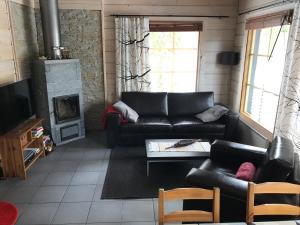 a living room with a leather couch and a fireplace at Rukan Sarastus in Ruka