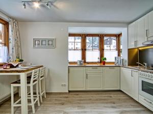 a kitchen with white cabinets and a table at Landhaus Winkelmatten in Schönau am Königssee