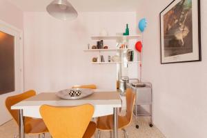 Apartamento Jardin de Santa Paula في إشبيلية: غرفة طعام مع طاولة بيضاء وكراسي صفراء