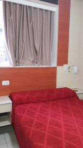 a red bed in a room with a window at Hotel Micro in Rosario