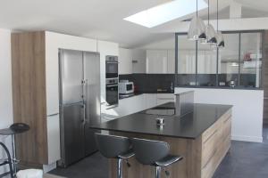 a kitchen with a black counter and a refrigerator at L'Île de Lumière in Rivedoux-Plage
