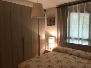1 dormitorio con cama, ventana y lámpara en Monolocale con giardino, en San Benedetto del Tronto