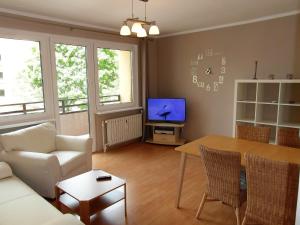 a living room with a couch and a table and a tv at Wolin-Travel Apartament Dom przy Parku in Międzyzdroje
