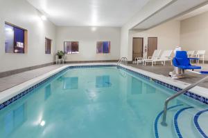 una piscina en una habitación de hotel con sillas azules en Travelodge by Wyndham Longmont, en Longmont