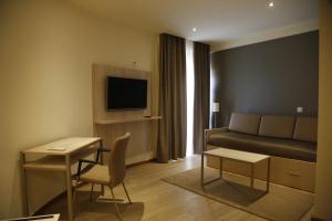 Hotel Ponte Sor في بونتي دي سور: غرفة في الفندق مع أريكة وسرير وطاولة