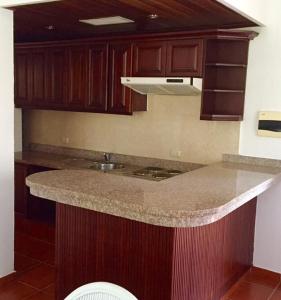 cocina con encimera de granito y armarios de madera en The Golf Suites, en Punta Cana