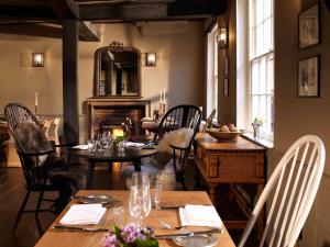 uma sala de jantar com mesas e cadeiras e uma lareira em The Crown em Amersham