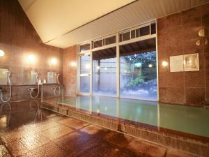 a bathroom with a swimming pool and a large window at Ryokan Hirayama in Ueki