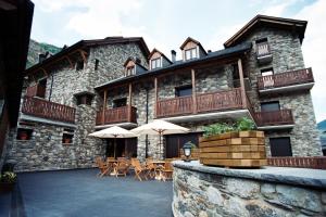 a large stone building with tables and umbrellas at Apartamentos Les Picardes in Espot