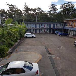 un estacionamiento con autos estacionados frente a un edificio en Chelsea Motor Inn, en Coffs Harbour