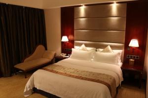 a hotel room with a large bed and a chair at Rongjiang Hotel in Jieyang